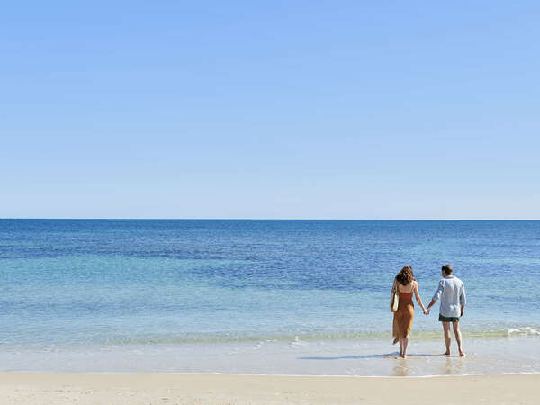 a man standing on top of a sandy beach next to the ocean