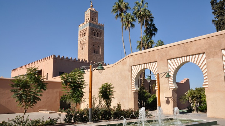 a clock tower in front of Koutoubia Mosque