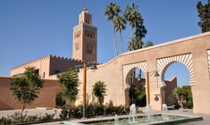 a clock tower in front of Koutoubia Mosque