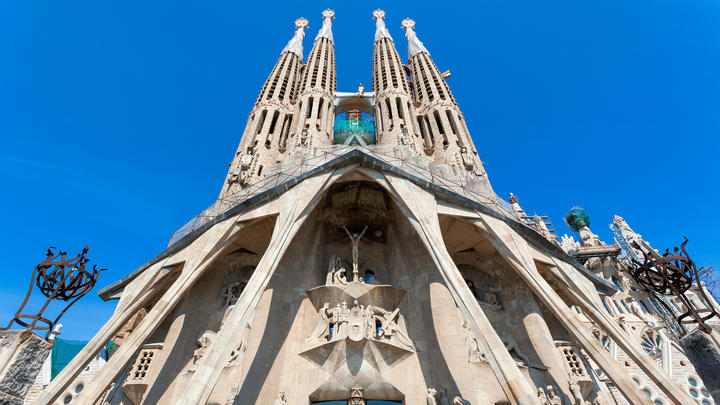 a large clock tower in the background with Sagrada Família in the background