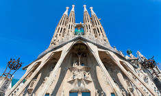 a large clock tower in the background with Sagrada Família in the background