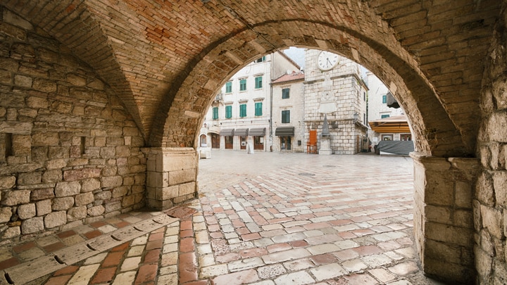 a stone building that has a bench in front of a brick wall