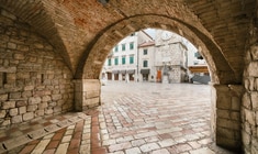 a stone building that has a bench in front of a brick wall