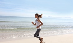 a woman throwing a frisbee at the beach