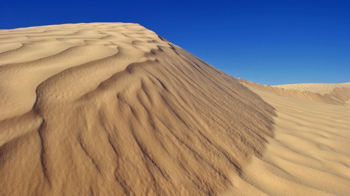 una montaña cubierta de nieve con Dunas de Algodones en el fondo