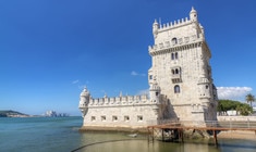 a castle with water in front of Belém Tower