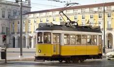 a yellow train traveling down train tracks near a building