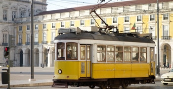 a yellow train traveling down train tracks near a building