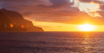 a sunset over a beach next to the ocean