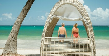a couple of people standing in a beach hut with a tree