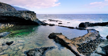 una playa rocosa con cuerpo de agua y una costa rocosa
