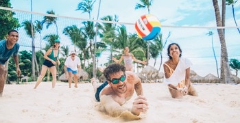 a group of people playing volleyball on a beach